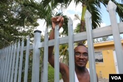 Kenneth Graham can’t grasp the costs he will face to repair water leaks and the broken fence around his property. His biggest concern, however, is lack of electricity in the neighborhood, for the sake of his newborn daughter. (Photo: R. Taylor / VOA)