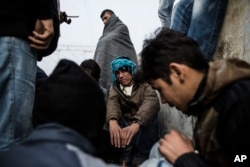 A group of Afghan refugees warm themselves near a fire at at the railway station of Sid, Serbia, where Serbian authorities send them to Croatia, Nov. 6, 2015.