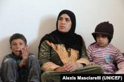 Seorang perempuan Suriah bersama dua anaknya di dalam apartemen mereka di Mafraq, sebelah utara Yordania. Suaminya tetap tinggal di Suriah. (Courtesy UNICEF/Alexis Masciarelly)