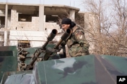 FILE - A Syrian army soldier stands on top of a vehicle carrying a gun in Salma, Syria, Jan. 22, 2016.