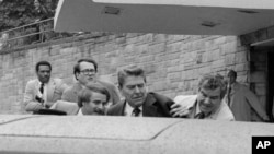 President Ronald Reagan is shoved into a limousine by secret service agents after being shot outside a Washington hotel, March 30, 1981.