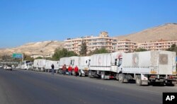 FILE - A convoy of humanitarian aid waits in front of the United Nations Relief and Works Agency (UNRWA) offices before making their way into the government besieged rebel-held towns of Madaya, al-Zabadani and al-Moadhamiya in the Damascus countryside, as