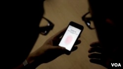 An Apple employee shows a journalist how to use the fingerprint scanner in the iPhone 5S in Beijing, China. (AP) ​