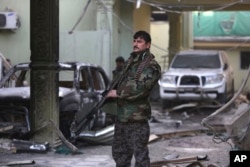 An Afghan security forces member stands guard at the Spanish Embassy after an attack in Kabul, Afghanistan, Dec. 12, 2015.