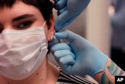 Maddie McFarland receives an ear piercing in Ann Arbor Michigan. (AP Photo/Carlos Osorio)