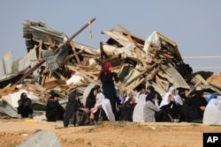 Bedouin women sit outside a demolished structure in the southern village of Umm al-Hiran, Wednesday, Jan. 18, 2017.