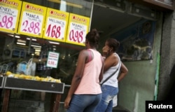 FILE - Women look at prices at a food market in Rio de Janeiro, Brazil, Jan. 21, 2016.