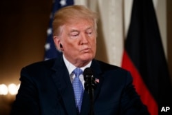 President Donald Trump listens to a question during a news conference with German Chancellor Angela Merkel in the East Room of the White House, April 27, 2018, in Washington.