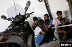 FILE - Migrants from Pakistan and Bangladesh wait after being detained by Turkish authorities at a bus terminal in the resort town of Bodrum, Turkey, Sept. 4, 2015.