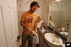 Federal contractor Chris Erickson paints his bathroom, Jan., 4, 2019, in North Salt Lake, Utah. Erickson says he'll run out of vacation days if the shutdown continues. The father of three from Salt Lake City will then crack into his savings, and he'll likely postpone a 14th wedding anniversary trip with his wife to a cabin. Erickson said he likely won't get the chance for reimbursement for the lost days because he's a contractor.