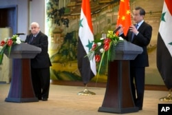 Menteri Luar Negeri China Wang Yi (kanan) dalam pertemuan dengan pers bersama Menlu Suriah Walid al-Moallem di Beijing, China (24/12)