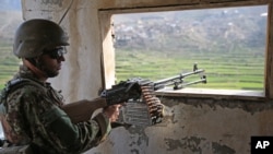 FILE - An Afghan National Army (ANA) soldier stands guard in Narai military camp in Ghazi Abad district, Feb. 23, 2014.