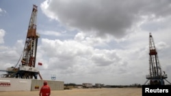 Un trabajador de un campo petrolero camina junto a las plataformas de perforación en un pozo petrolero operado por la petrolera estatal venezolana PDVSA, en la rica franja del Orinoco, el 16 de abril de 2015.