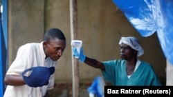 Un agent de santé prend la température d'un homme entrant dans le centre de traitement Ebola ALIMA (The Alliance for International Medical Action) à Beni, en RDC, le 1er avril 2019.