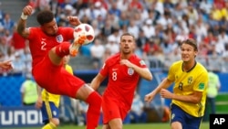 England's Kyle Walker, left, kicks the ball front of England's Jordan Henderson, center, and Sweden's Albin Ekdal, right, at the 2018 soccer World Cup in Samara, Russia. (AP Photo/Matthias Schrader )