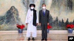 FILE - Taliban co-founder Mullah Abdul Ghani Baradar, left, and Chinese Foreign Minister Wang Yi pose for a photo during their meeting in Tianjin, China, July 28, 2021. 