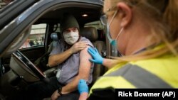 Spencer Jensen, music teacher at the Legacy Preparatory Academy receives the COVID-19 vaccine at the Davis County Legacy Center, Jan. 12, 2021, in Farmington, Utah. (AP Photo/Rick Bowmer)