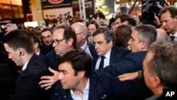 Conservative presidential candidate Francois Fillon, center right, makes his way while visiting the Agriculture Fair in Paris, March 1, 2017. Fillon is refusing to quit the race despite receiving a summons Wednesday to face charges for alleged fake parliamentary jobs for his family. 