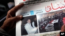 An Egyptian in Cairo holds the Al-Ahram newspaper fronted by a picture of Mohammed Badie, the supreme leader of the Muslim Brotherhood, left, and pictures of flag-draped coffins containing the bodies of slain off-duty policemen, Aug. 20, 2013.