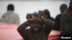Seorang migran yang dicegat dalam sebuah kapal di lepas pantai Laut Tengah, memberikan isyarat kepada perahu penyelamat setelah tiba di Pelabuhan Malaga, selatan Spanyol, 18 Juli 2018.
