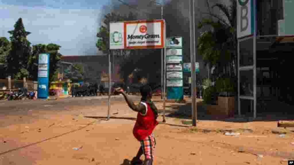 Un jeune burkinabé jette une pierre sur des policiers lors de la manifestation contre le président du Burkina Faso dont le gouvernement tente de modifier la constitution pour un nouveau mandat à la tête du pays, Ouagadougou, au Burkina Faso, le mardi 28 octobre 2014. 