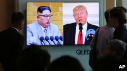 People watch a TV screen showing President Donald Trump, right, and North Korean leader Kim Jong Un during a news program at the Seoul Railway Station, April 21, 2018. 