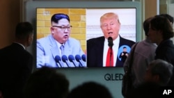 People watch a TV screen showing President Donald Trump, right, and North Korean leader Kim Jong Un during a news program at the Seoul Railway Station, April 21, 2018. 