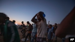 Tigray men who fled the conflict in Ethiopia's Tigray region, run to recieve cooked rice from charity organization Muslim Aid, at Umm Rakouba refugee camp in Qadarif, eastern Sudan, Nov. 27, 2020.