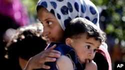 A Syrian refugee carries her sister through a camp set up near the village of Ketermaya in Lebanon in March.