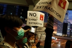 People hold placards during a protest against a proposed extradition bill, near the Legislative Council building in Hong Kong, June 13, 2019.