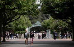 FILE - People walk in front of Sather Gate on the University of California-Berkeley campus in Berkeley, Calif., July 18, 2019.