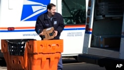 FILE - A U.S. Postal Service employee loads parcels outside a post office in Wheeling, Ill., Jan. 29, 2024. 