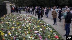 People look at flowers outside Windsor Castle in Windsor, England, to pay tribute to Britain's Prince Philip, the irascible and tough-minded husband of Queen Elizabeth II, April 11, 2021.
