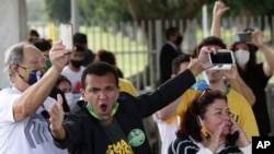 Supporters of Brazilian President Jair Bolsonaro, not all wearing face masks amid the coronavirus pandemic, yell at journalists, calling them "trash" and "coup plotters," after the president left Alvorada palace in Brasilia, Brazil, May 25, 2020.
