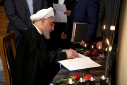 A handout picture provided by the Iranian Presidency on Jan. 15, 2020, shows President Hassan Rouhani signing a book carrying the names of the victims of the Ukraine Flight 752 downing.