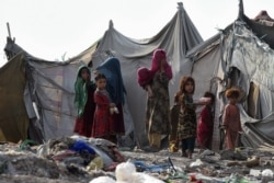FILE - Children of Afghan refugees play outside tents in Afghan Basti area on the outskirts of Lahore, Pakistan, June 19, 2021.