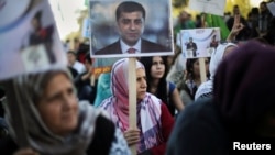  A Kurdish woman living in Athens, Greece, holds a photo of arrested HDP co-leader Selahattin Demirtas, during a demonstration against the Turkish government following the arrests of pro-Kurdish officials in Turkey, Nov. 5, 2016.