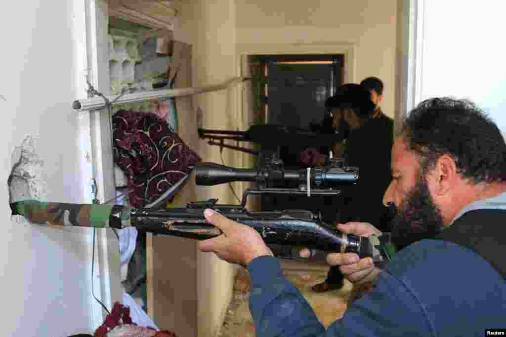 Rebel fighters aim their weapons inside a building near the frontline against forces loyal to Syria's President Bashar al-Assad in al-Manshiyeh neighborhood in Deraa, Dec. 7, 2014.