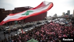 Demonstrators stand next to Lebanese army soldiers during ongoing anti-government protests at a highway in Jal el-Dib, Lebanon, Oct. 23, 2019. 