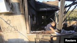An Israeli police officer inspects a house that was badly damaged from a suspected attack by Jewish extremists on two houses at Kafr Duma village near the West Bank city of Nablus, July 31, 2015.