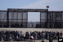 Para migran memadati tembok perbatasan AS sementara agen Patroli Perbatasan AS berjaga, terlihat dari kota Ciudad Juarez, Meksiko.
