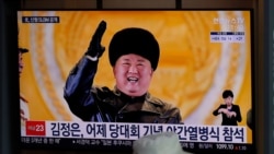 A man wearing a face mask sits in front of a TV screen showing North Korean leader Kim Jong Un, at the Seoul Railway Station in Seoul, South Korea, Friday, Jan. 15, 2021. The letters read "Kim Jong Un attended stage in Thursday night's parade…