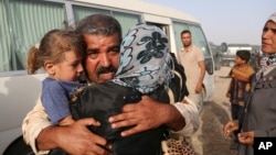 Abdul Rahman Ismail, an Iraqi soldier who has been targeted by Islamic State extremists who destroyed his house two years ago, is reunited with his family after they were able to flee their Islamic State held town, as displaced Iraqi families gather outsi