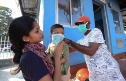 A man wearing a surgical mask makes a child wear one outside the government general hospital where a student who had been in Wuhan is kept in isolation in Thrissur, Kerala state, India, Jan. 30, 2020.