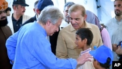 Katibu Mkuu Antonio Guterres akifuatana na waziri mkuu wa Pakistan Shahbaz Sharif akizungumza na watoto katika shule inayowapatia hifadhi. 