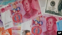 FILE - A man walks by a money exchange shop decorated with Chinese yuan in Hong Kong, Aug. 6, 2019.