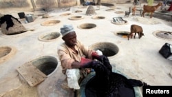 FILE - A man dyes fabrics in traditional styles in Kano, Nigeria.