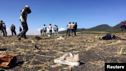 People walk past a part of the wreckage at the scene of the Ethiopian Airlines Flight ET 302 plane crash, near the town of Bishoftu, southeast of Addis Ababa, March 10, 2019.