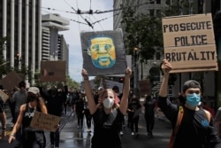 A woman holds a sign showing George Floyd, who died after being restrained by Minneapolis police, while marching on Market Street at a protest calling for an end to racial injustice and accountability for police in San Francisco, June 20, 2020.