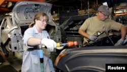 FILE - A female employee works alongside a male colleague at a Ford Motor Plant in Wayne, Michigan.